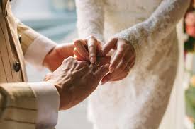 Bride and groom in white holding hands exchanging gifts